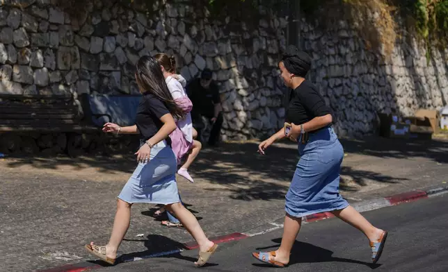 People run to take cover as a siren sounds a warning of incoming rockets fired from Lebanon, in Safed, northern Israel, Thursday, Sept. 26, 2024. (AP Photo/Ariel Schalit)