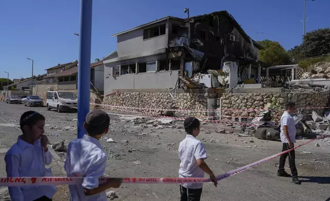 Kids look at a house damaged following a rocket attack from Lebanon, in Safed, northern Israel, on Saturday, Sept. 28, 2024. (AP Photo/Baz Ratner)