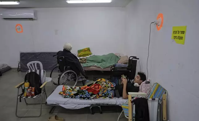 Israelis rest in a residential building bomb shelter to stay safe from rockets fired from Lebanon, in Kiryat Haim, northern Israel, on Tuesday, Sept. 24, 2024. (AP Photo/Baz Ratner)