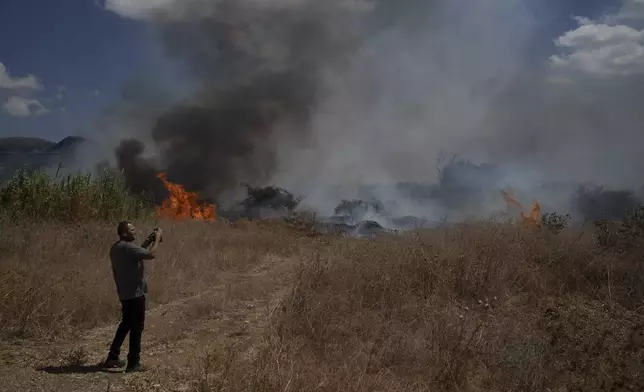 A person takes a picture with his phone of a fire burning in an area, following an attack from Lebanon, near the Kibbutz Snir, northern Israel, Monday, Sept. 16, 2024. (AP Photo/Leo Correa)