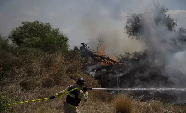 An Israeli firefighter works to extinguish a fire burning in an area, following an attack from Lebanon, near the Kibbutz Snir, northern Israel, Monday, Sept. 16, 2024. (AP Photo/Leo Correa)