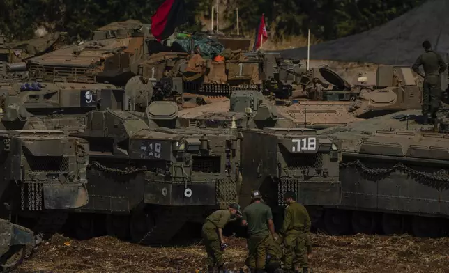 Israeli soldiers work on tanks and APC in northern Israel on Sunday, Sept. 29, 2024. (AP Photo/Ariel Schalit)