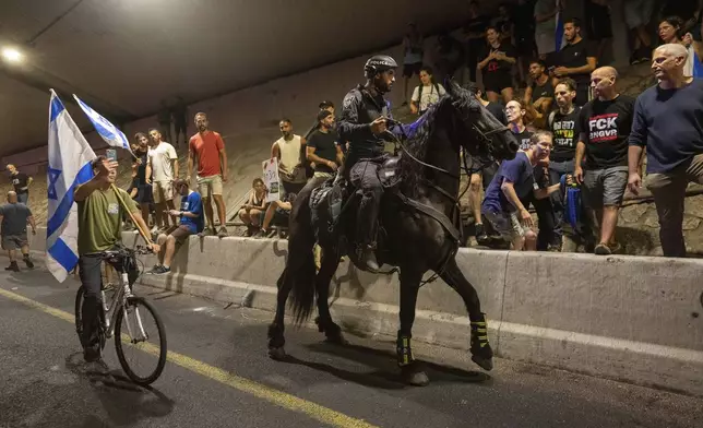 A police officer on a horse moves past people protesting for a deal for the immediate release of hostages held in the Gaza Strip by Hamas, in Tel Aviv, Israel, Sunday, Sept. 1, 2024. (AP Photo/Ohad Zwigenberg)