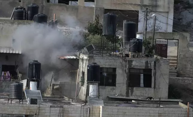 EDS NOTE: GRAPHIC CONTENT - An explosion is seen as three bodies lie motionless on rooftops in the West Bank town of in the West Bank town of Qatabiya during a raid, Thursday, Sept. 19, 2024. (AP Photo/Majdi Mohammed)