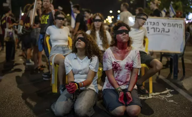 Blindfolded and bounded wrists activists take part in a protest against Prime Minister Benjamin Netanyahu's government and call for the release of hostages held in the Gaza Strip by the Hamas militant group, in Tel Aviv, Israel, Saturday, Aug. 31, 2024. (AP Photo/Ohad Zwigenberg)