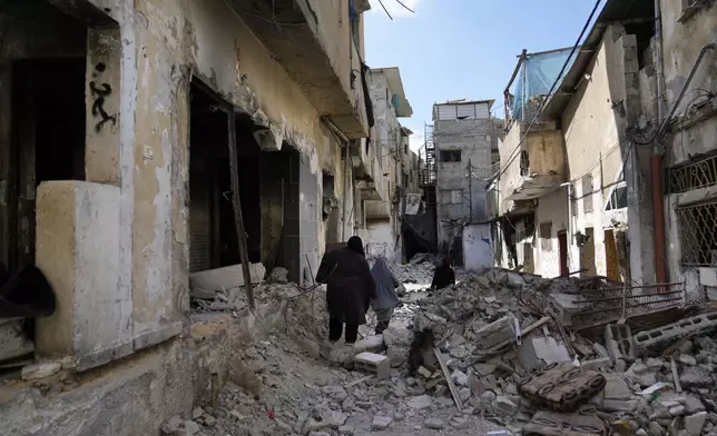 Palestinian refugees walk through the rubble of destroyed houses while they flee their homes during the Israeli army operation in the West Bank refugee camp of Tulkarem, in Tulkarem, Thursday, Sept. 5, 2024. (AP Photo/Nasser Nasser)