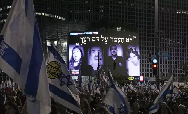 People gather in front of a large screen displaying photos of hostages held in the Gaza Strip by the Hamas militant group, during a protest against Prime Minister Benjamin Netanyahu's government and call for their release, in Tel Aviv, Israel, on Saturday, Aug. 31, 2024. (AP Photo/Ohad Zwigenberg)