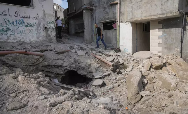 Palestinians walk past a damaged building following an Israeli military operation in the West Bank city of Jenin on Friday, Sept. 6, 2024. (AP Photo/Majdi Mohammed)