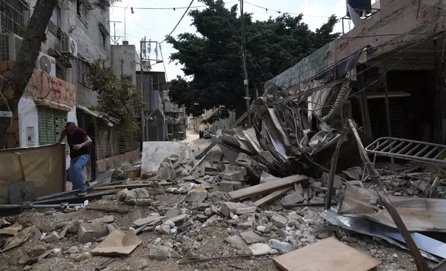 A Palestinian refugee walks through the rubble of a building that was destroyed during the Israeli army operation in the West Bank refugee camp of Tulkarem, in Tulkarem, Thursday, Sept. 5, 2024. (AP Photo/Nasser Nasser)