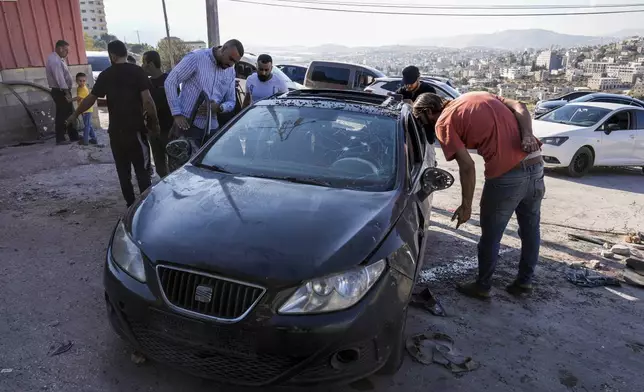 Palestinians look at a damaged car following an Israeli airstrike in Tubas, West Bank, Thursday, Sept. 5, 2024. Palestinian health officials say Israeli strikes in the occupied West Bank killed five people. Israel has been carrying out large-scale raids in the territory over the past week that it says are aimed at dismantling militant groups and preventing attacks. (AP Photo/Majdi Mohammed)