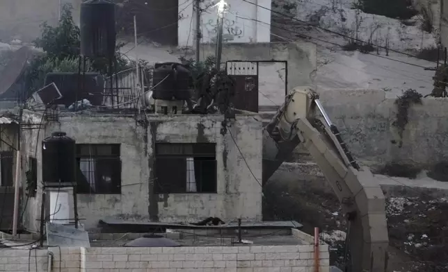 EDS NOTE: GRAPHIC CONTENT - Israeli soldiers look over a rooftop where two lie motionless in the West Bank town of Qatabiya during a raid, Thursday, Sept.19, 2024. (AP Photo/Majdi Mohammed)