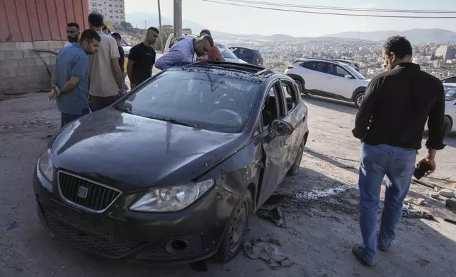 Palestinians look at a damaged car following an Israeli airstrike in Tubas, West Bank, Thursday, Sept. 5, 2024. Palestinian health officials say Israeli strikes in the occupied West Bank killed five people. Israel has been carrying out large-scale raids in the territory over the past week that it says are aimed at dismantling militant groups and preventing attacks. (AP Photo/Majdi Mohammed)