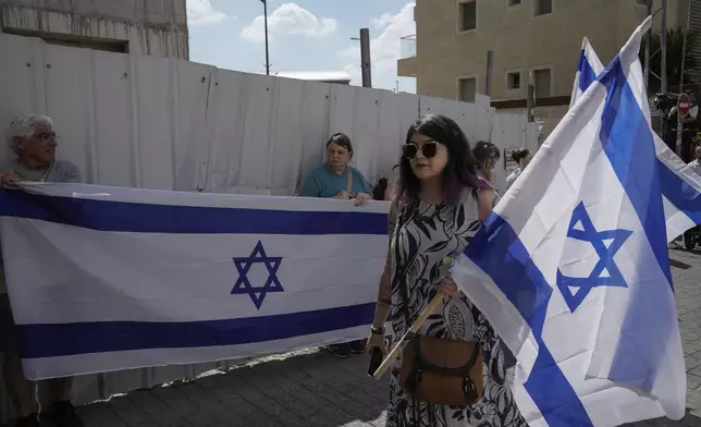 Mourners wave Israeli flags as they accompany the family of Israeli-American hostage Hersh Goldberg-Polin, who was killed in Hamas captivity in the Gaza Strip, on their way to his funeral in Jerusalem, Monday, Sept. 2, 2024. Israel said Sunday it recovered the bodies of six hostages, including Goldberg-Polin's. (AP Photo/Leo Correa)