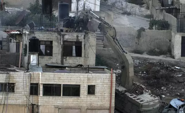 EDS NOTE: GRAPHIC CONTENT - Israeli soldiers look over a rooftop where two bodies lie motionless in the West Bank town of Qatabiya during a raid, Thursday, Sept. 19, 2024. (AP Photo/Majdi Mohammed)