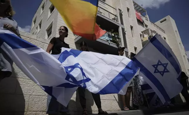 Mourners wave Israeli flags as they accompany the family of Israeli-American hostage Hersh Goldberg-Polin, who was killed in Hamas captivity in the Gaza Strip, on their way to his funeral in Jerusalem, Monday, Sept. 2, 2024. Israel said Sunday it recovered the bodies of six hostages, including Goldberg-Polin's. (AP Photo/Leo Correa)