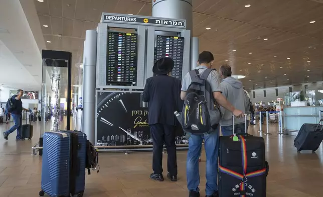 Travelers check departing flights at Ben Gurion International Airport near Tel Aviv, Israel, Monday Sept. 2, 2024. Outgoing flights at the airport were halted for two hours on Monday morning as part of a general strike launched in response to the deaths of hostages held in Gaza. (AP Photo/Ohad Zwigenberg)