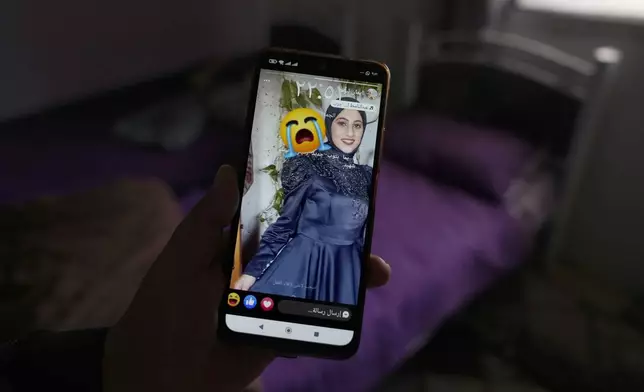 Palestinian Barakat Jabr, 15, displays a photo of his sister Bana Bakr, 13, on his mobile phone in her bedroom at the family house, as he waits for her funeral, in the West Bank village of Qaryut, south of Nablus, Saturday, Sept. 7, 2024. Bakr was killed by Israeli fire the Palestinian health ministry said. The Israeli army said they were reviewing the incident. (AP Photo/Nasser Nasser)