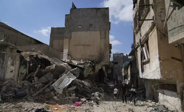 Palestinian refugees walk past the rubble of houses that were destroyed during the Israeli army operation in the West Bank refugee camp of Tulkarem, in Tulkarem, Thursday, Sept. 5, 2024. (AP Photo/Nasser Nasser)