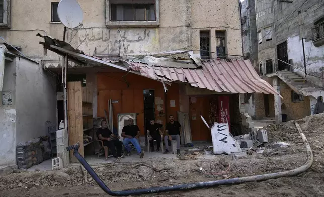 Palestinian refugees sit in front of their shops that were damaged during the Israeli army operation in the West Bank refugee camp of Tulkarem, in Tulkarem, Thursday, Sept. 5, 2024. (AP Photo/Nasser Nasser)