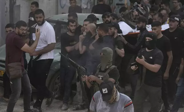 A masked gunman fires in the air during the funeral of Palestinian men who were killed in an Israeli military operation, in Jenin, West Bank, Friday, Sept. 6, 2024. (AP Photo/Majdi Mohammed)