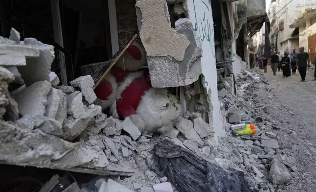 Palestinian refugees walk past rubble of partly destroyed houses in the West Bank refugee camp of Tulkarem, during an Israeli army operation in Tulkarem, Thursday, Sept. 12, 2024. (AP Photo/Nasser Nasser)