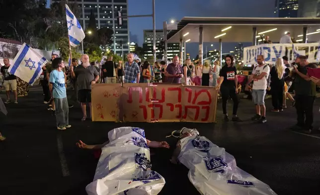 Demonstrators lie on the ground in white plastic bags simulating dead bodies, take part in a protest against Israeli Prime Minister Benjamin Netanyahu's government in Tel Aviv, Israel, Saturday, Aug. 31, 2024. (AP Photo/Ohad Zwigenberg)