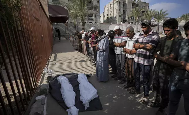 Mourners pray over the covered bodies of Palestinians who were killed in an Israeli airstrike on a crowded tent camp housing Palestinians displaced by the war in the Muwasi, outside the hospital morgue in Deir al-Balah, Gaza Strip, Tuesday, Sept. 10, 2024. (AP Photo/Abdel Kareem Hana)