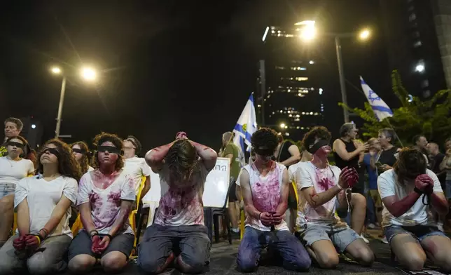 Blindfolded and bounded wrists activists take part in a protest against Israeli Prime Minister Benjamin Netanyahu's government and call for the release of hostages held in the Gaza Strip by the Hamas militant group in Tel Aviv, Israel, Saturday, Aug. 31, 2024. (AP Photo/Ohad Zwigenberg)