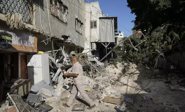 Palestinian refugees walk outside their partly destroyed houses in the West Bank refugee camp of Tulkarem, during an Israeli army operation in Tulkarem, Thursday, Sept. 12, 2024. (AP Photo/Nasser Nasser)