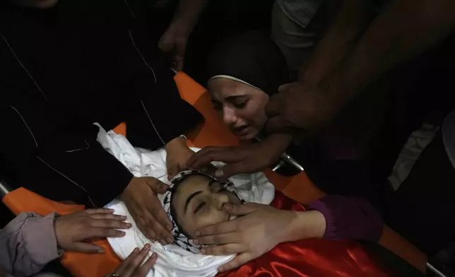 Mourners take the last look at the body of Palestinian girl Bana Bakr, 13, at the family house during her funeral in the West Bank village of Qaryut, south of Nablus, Saturday, Sept. 7, 2024. Bakr was killed by Israeli fire, the Palestinian health ministry said. The Israeli army said they were reviewing the incident. (AP Photo/Nasser Nasser)