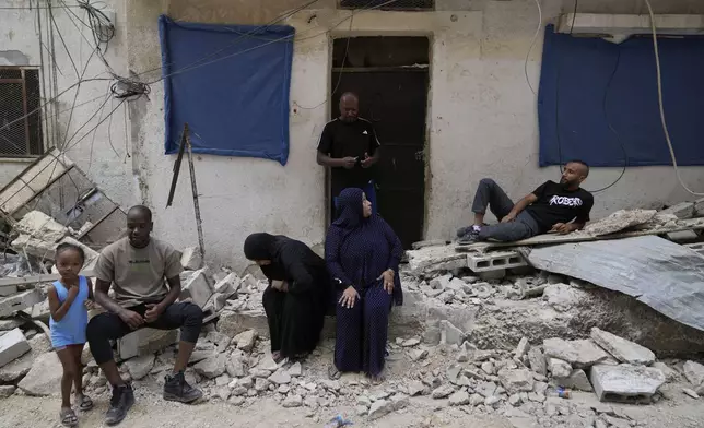 Palestinian refugees sit at the rubble of their partly destroyed house that was damaged during the Israeli army operation in the West Bank refugee camp of Tulkarem, in Tulkarem, Thursday, Sept. 5, 2024. (AP Photo/Nasser Nasser)