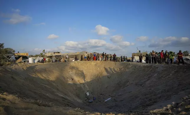 Palestinians look at the destruction after an Israeli airstrike on a crowded tent camp housing Palestinians displaced by the war in Muwasi, Gaza Strip, Tuesday, Sept. 10, 2024. An Israeli strike killed at least 40 people and wounded 60 others early Tuesday, Palestinian officials said. Israel said it targeted "significant" Hamas militants, allegations denied by the militant group. (AP Photo/Abdel Kareem Hana)