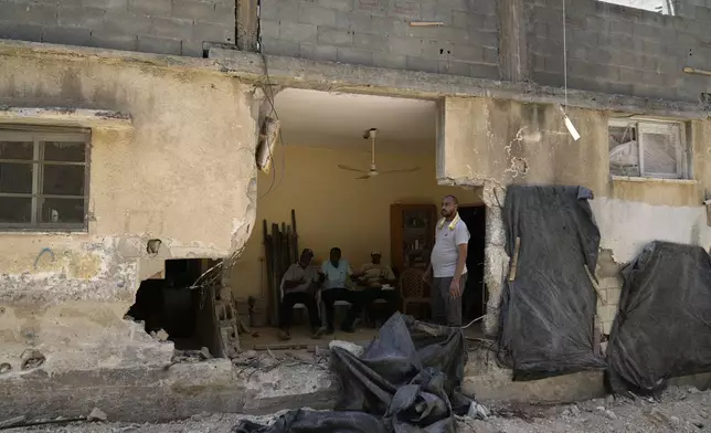 Palestinian refugees sit inside their partly destroyed house that was damaged during the Israeli army operation in the West Bank refugee camp of Tulkarem, in Tulkarem, Thursday, Sept. 5, 2024. (AP Photo/Nasser Nasser)