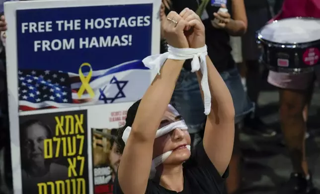 A woman wears a blindfold during a protest calling for a cease-fire deal and the immediate release of hostages held in Gaza by Hamas in Tel Aviv, Israel on Wednesday, Sept. 4, 2024. (AP Photo/Ariel Schalit)