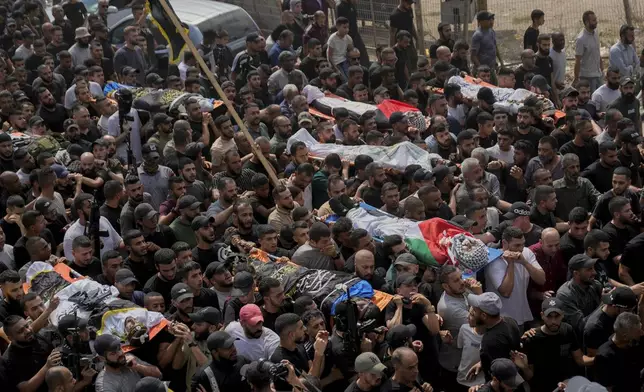 Mourners carry the bodies of Palestinian men who were killed during an Israeli military operation, some draped in the Palestinian and the Islamic Jihad militant group flags, during their funeral in Jenin, West Bank, Friday, Sept. 6, 2024. (AP Photo/Nasser Nasser)