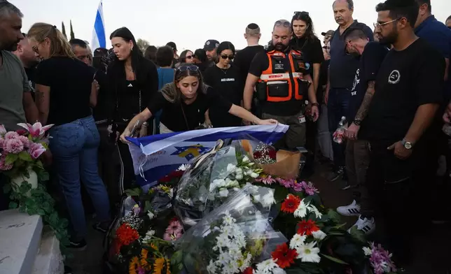 A mourner lays an Israeli flag on the grave of slain hostage Alexander Lobanov, who was killed in Hamas captivity in the Gaza Strip, in Ashkelon, southern Israel, Sunday, Sept. 1, 2024. (AP Photo/Tsafrir Abayov)