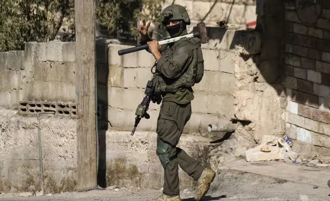 An Israeli soldier flashes a V-sign to photographers during an army raid in Tubas, West Bank, on Wednesday, Sept. 11, 2024. (AP Photo/Majdi Mohammed)