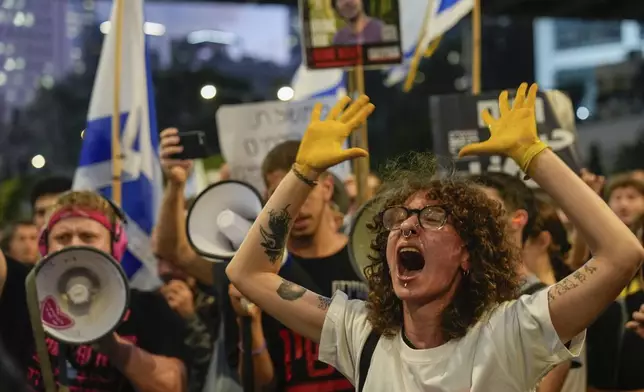 A demonstrator with her hands painted in yellow calls for a cease-fire deal and the immediate release of hostages held in Gaza by Hamas during a protest in Tel Aviv, Israel on Wednesday, Sept. 4, 2024. (AP Photo/Ariel Schalit)