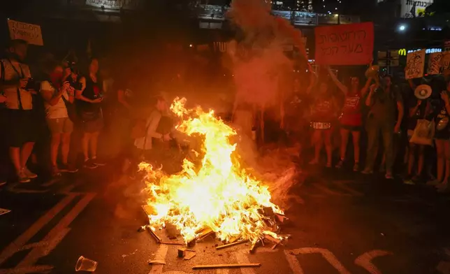 Demonstrators light a bonfire during a protest demanding a cease-fire deal and the immediate release of hostages held by Hamas in the Gaza Strip on Thursday, Sept. 5, 2024, in Tel Aviv, Israel. (AP Photo/Ohad Zwigenberg)