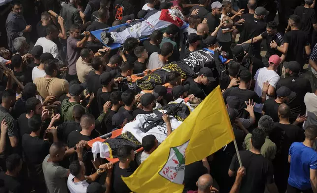 Mourners carry the bodies of Palestinian men who were killed during an Israeli military operation, some draped in the Palestinian and the Islamic Jihad militant group flags, during their funeral in Jenin, West Bank, Friday, Sept. 6, 2024. (AP Photo/Nasser Nasser)