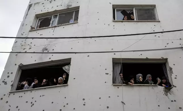 Mourners watch the funeral of Palestinian men who were killed during an Israeli military operation, from a building damaged with bullet holes, in Jenin, West Bank, Friday, Sept. 6, 2024. (AP Photo/Majdi Mohammed)