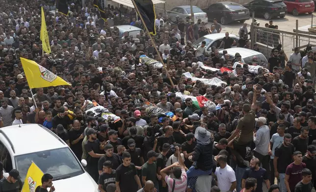 Mourners carry the bodies of Palestinian men who were killed during an Israeli military operation, some draped in the Palestinian and the Islamic Jihad militant group flags, during their funeral in Jenin, West Bank, Friday, Sept. 6, 2024. (AP Photo/Nasser Nasser)