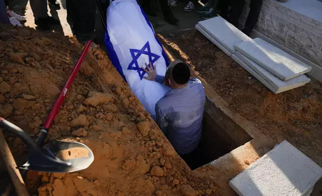 The coffin of the slain hostage Almog Sarusi, who was killed in Hamas captivity in the Gaza Strip, is placed in a grave during his funeral at a cemetery in Ra'anana, Israel, Sunday, Sept. 1, 2024. (AP Photo/Ariel Schalit)