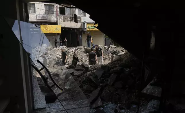 Palestinians stand in front a damaged shop as they walk on a destroyed street during a military operation in the West Bank city of Jenin, Sunday, Sept. 1, 2024. (AP Photo/Majdi Mohammed)