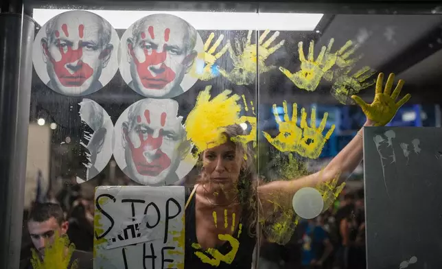 Demonstrators marks their hands on a window of a bus stop with photos of Israeli Prime Minister Benjamin Netanyahu, during a protest demanding a cease-fire deal and the immediate release of hostages held by Hamas in the Gaza Strip on Thursday, Sept. 5, 2024, in Tel Aviv, Israel. (AP Photo/Ohad Zwigenberg)