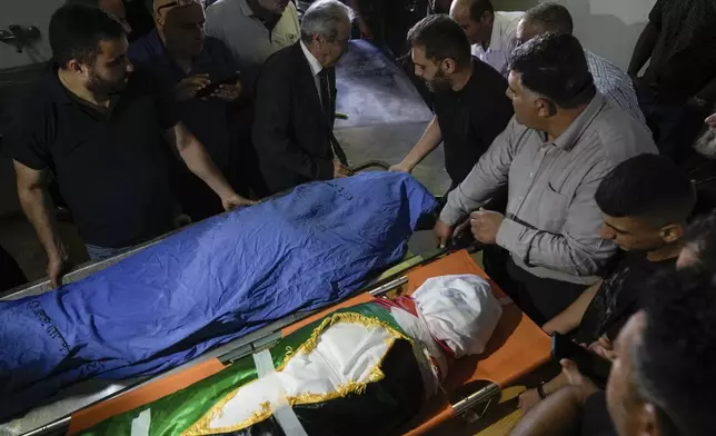 Palestinian mourners gather around the covered bodies of Turkish-American Aysenur Ezgi Eygi, 26, and Bana Bakr, 13, at a morgue in Nablus, West Bank, Saturday, Sept. 7, 2024. Witnesses said Eygi, was fatally shot by Israeli forces in a moment of calm after clashes between Palestinians and Israeli forces near Nablus on Friday. Bakr was also killed by Israeli fire the Palestinian health ministry said, while the Israeli army said they were reviewing the incident which happened during clashes between Palestinians and Israeli nationals in an area south of Nablus. (AP Photo/Majdi Mohammed)