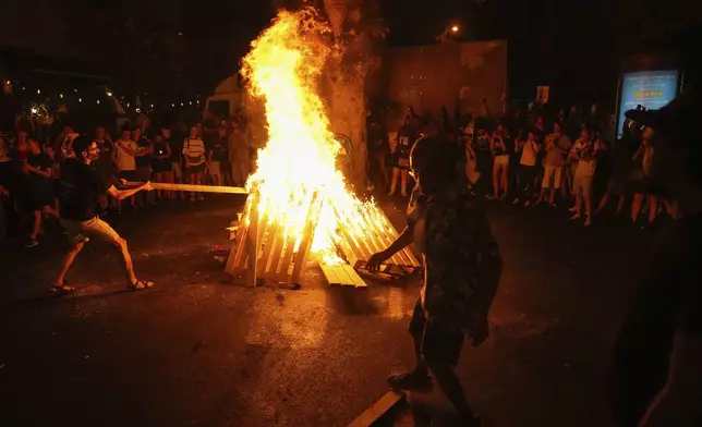 Demonstrators light a bonfire during a protest demanding a cease-fire deal and the immediate release of hostages held by Hamas in the Gaza Strip after the deaths of six hostages in the Palestinian territory, in Tel Aviv, Israel, on Monday, Sept. 2, 2024. (AP Photo/Ariel Schalit)