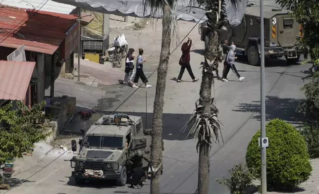 Israeli soldiers arrest a Palestinian man as others walk by with their hands up during a military operation in Jenin, West Bank, Thursday, Sept. 5, 2024. (AP Photo/Majdi Mohammed)