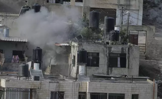 EDS NOTE: GRAPHIC CONTENT - An explosion is seen as three bodies lie motionless on rooftops in the West Bank town of Qatabiya during a raid, Thursday, Sept. 19, 2024. (AP Photo/Majdi Mohammed)