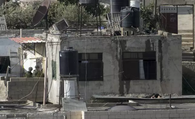 EDS NOTE: GRAPHIC CONTENT - Israeli soldiers stand near three bodies on rooftops in the West Bank town of Qatabiya during a raid, Thursday, Sept. 19, 2024. (AP Photo/Majdi Mohammed)